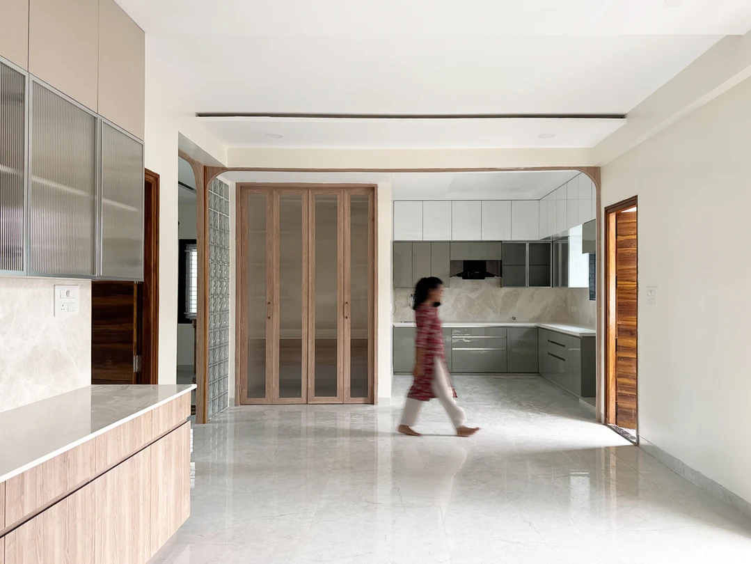 Open-plan grey modular kitchen with fluted-glass cabinets and glass-block partition on marble floor, Hyderabad