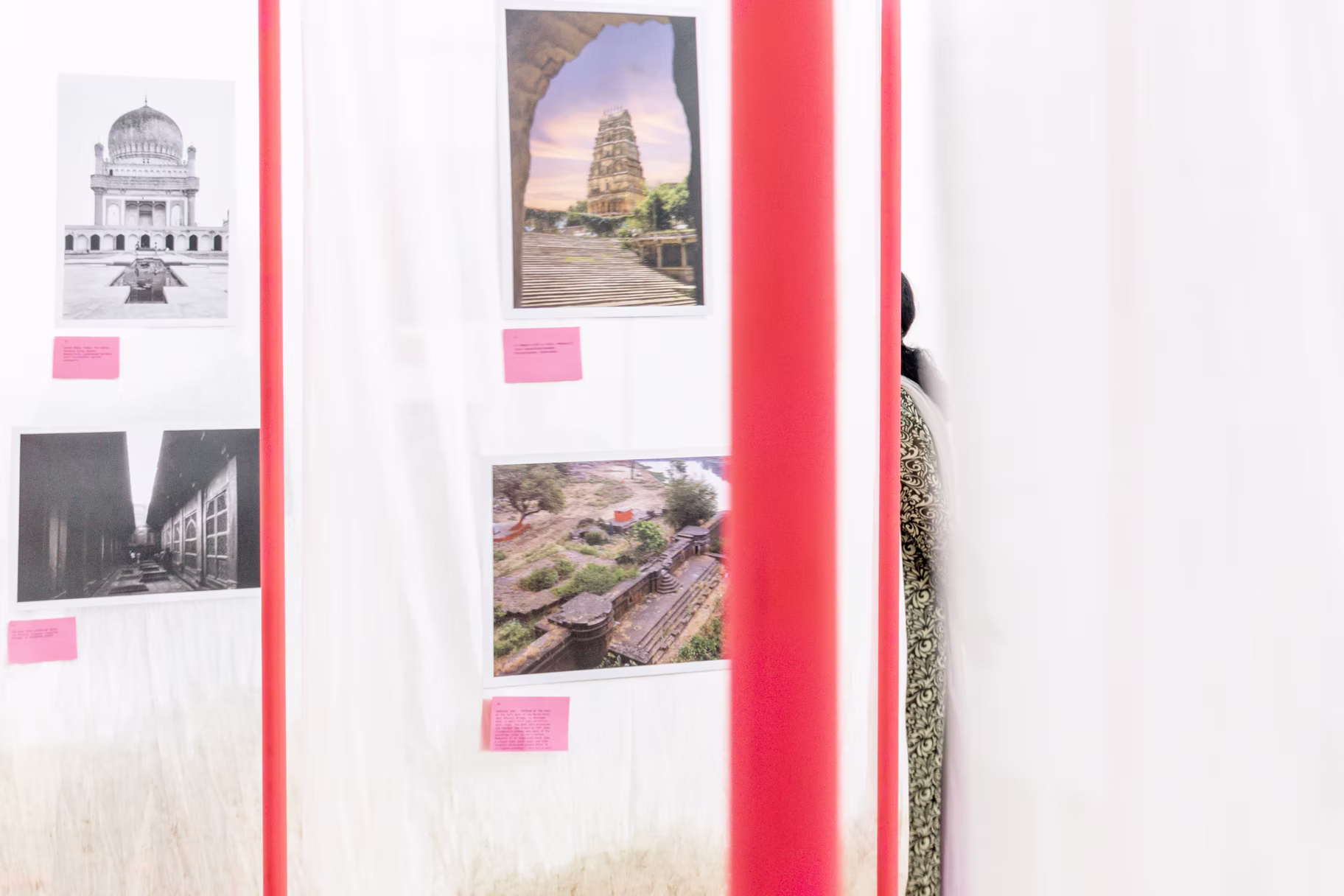 Suspended exhibition panels printing Hyderabad heritage views, a temple gopuram, Qutb Shahi tomb and stepped gardens