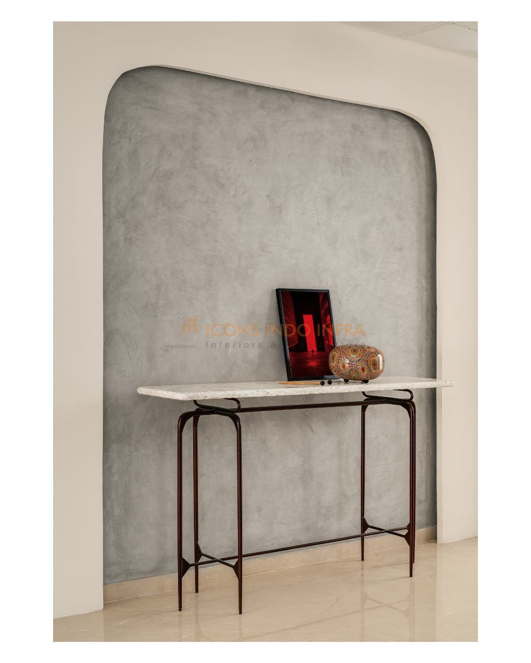 Foyer vignette in Hyderabad with slim metal console table against a textured grey arched plaster wall and decor accents