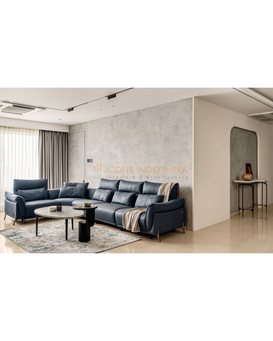 Living room in Hyderabad with navy leather L-shaped sofa, concrete-finish accent wall and nested marble coffee tables
