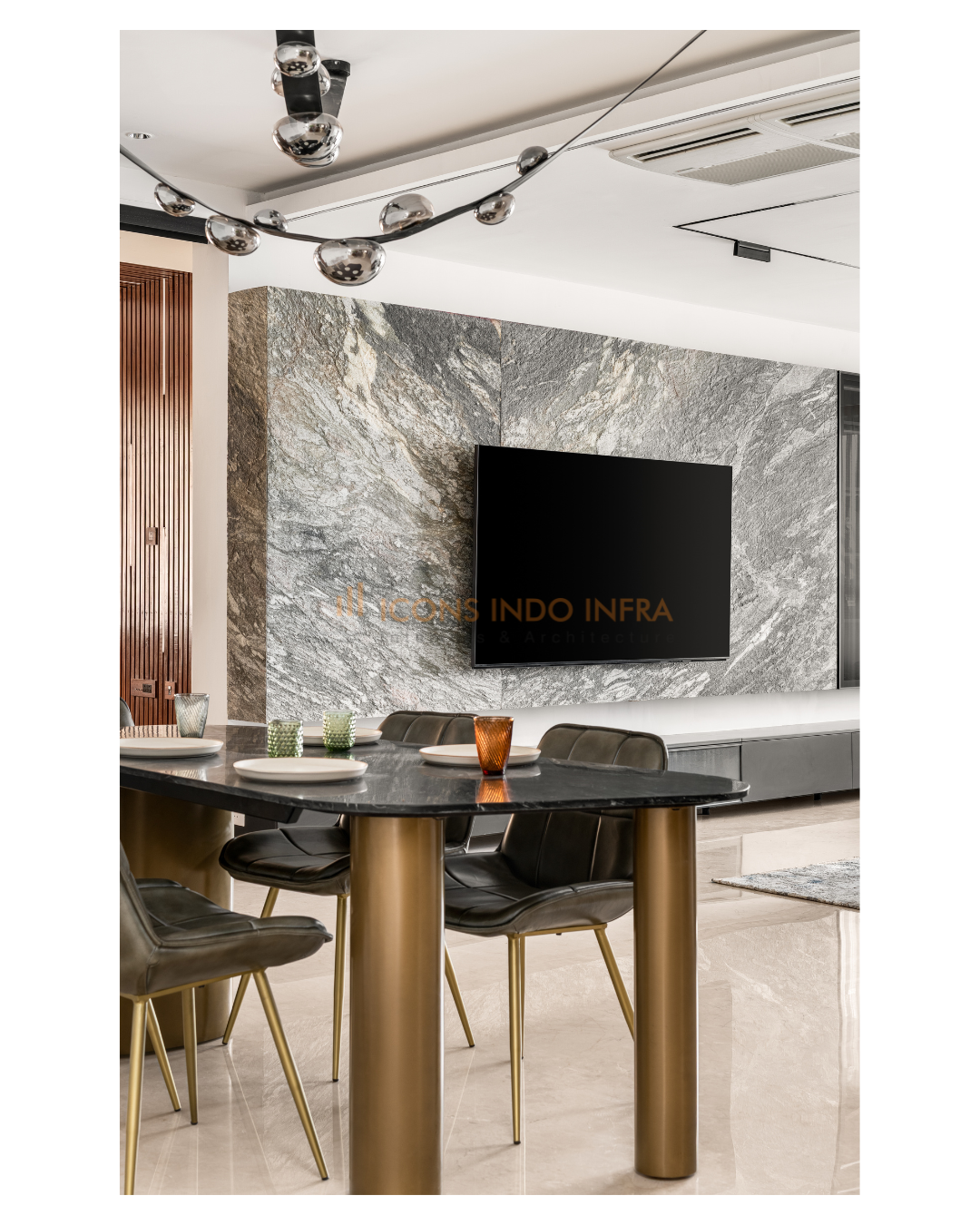 Dining area with grey marble TV feature wall, black sintered-stone table on brass legs and dark leather chairs, Hyderabad