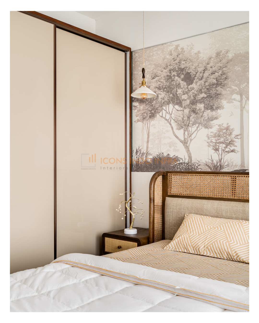 Guest bedroom corner close-up: cane headboard against a forest mural, ribbed sliding wardrobe and a brass pendant light