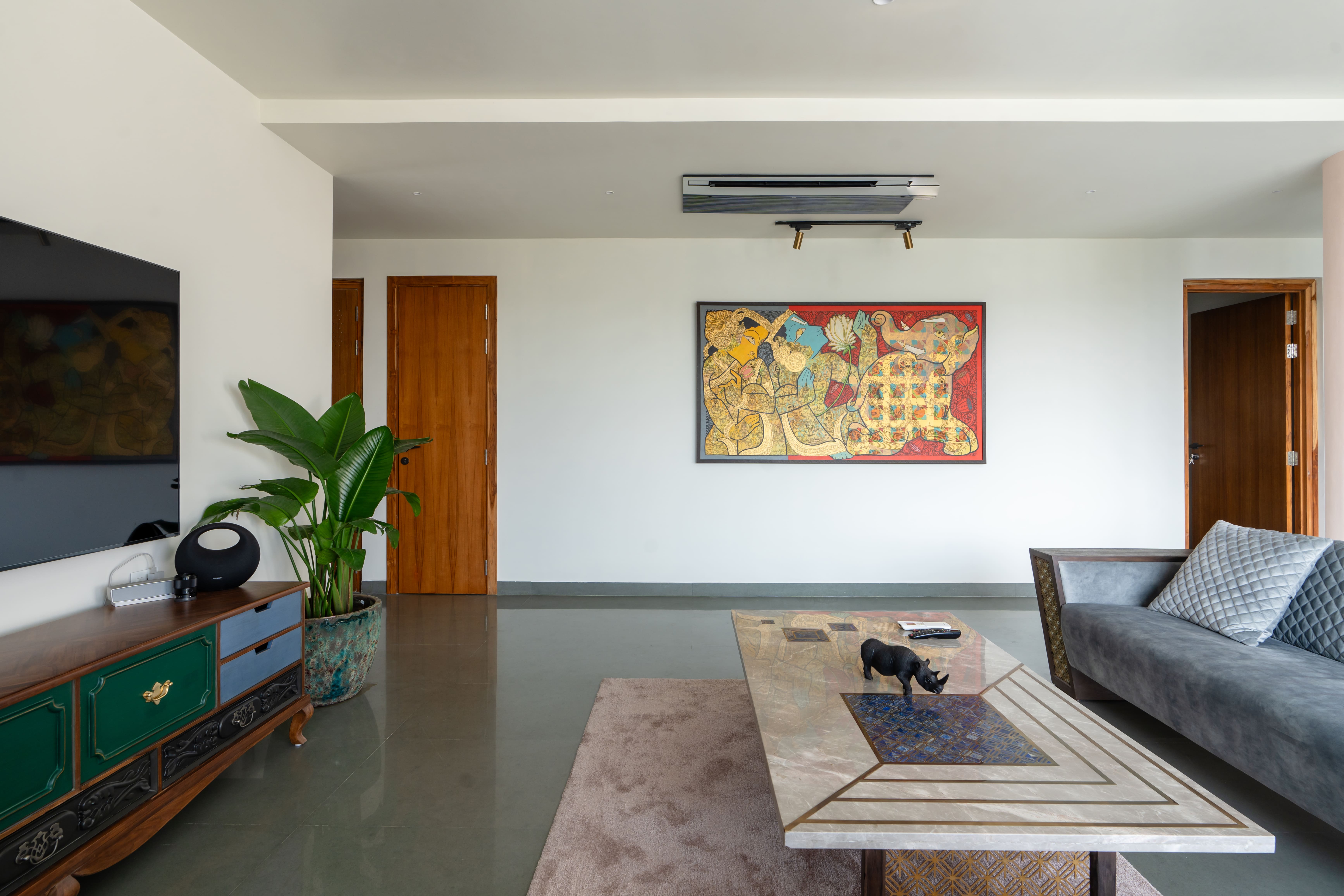 Living room framing an abstract painting, green painted console, grey sofa and marble coffee table on polished floors, Hyderabad