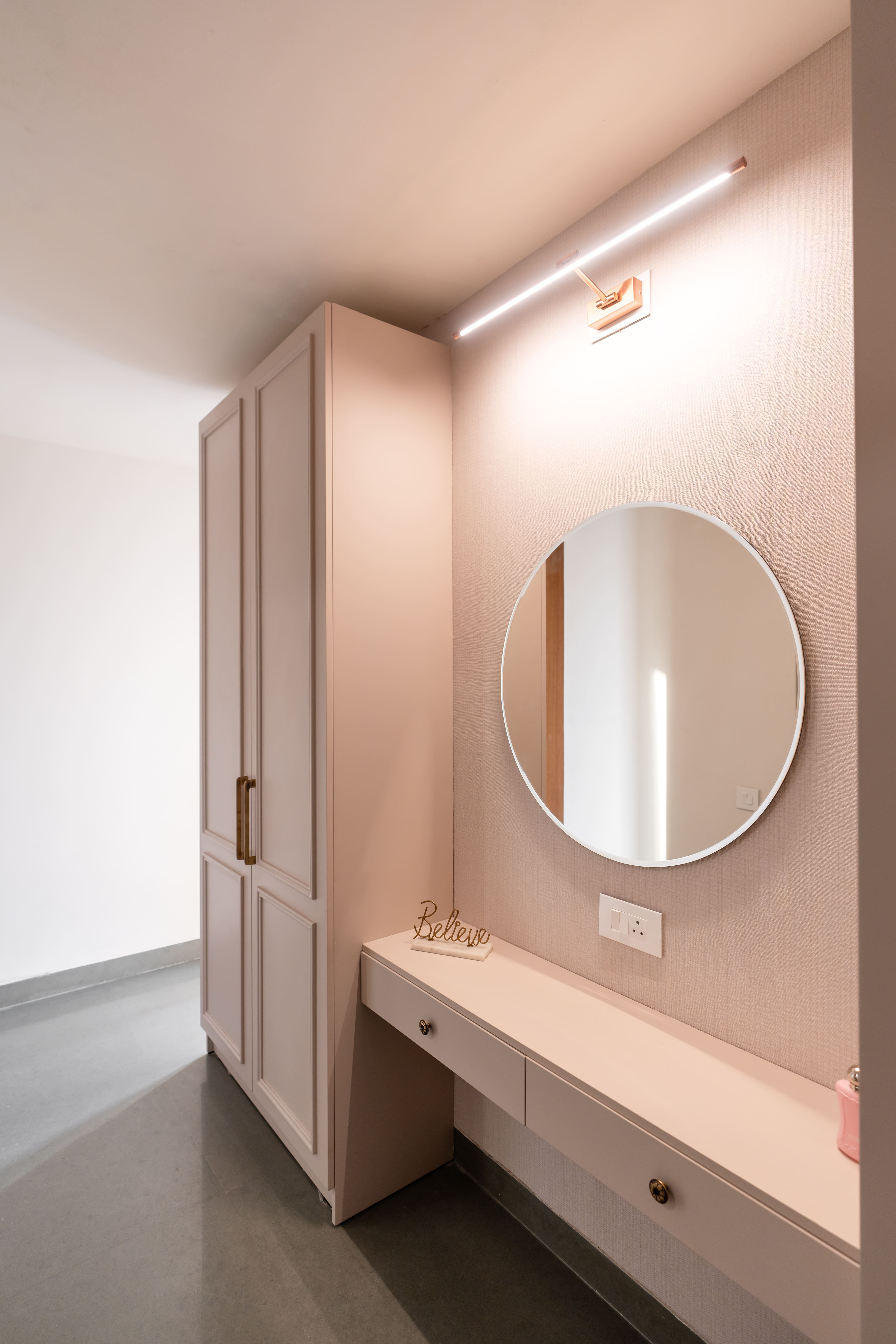 Blush-pink dressing nook with round wall mirror, LED picture light and floor-to-ceiling wardrobe, Hyderabad master bedroom