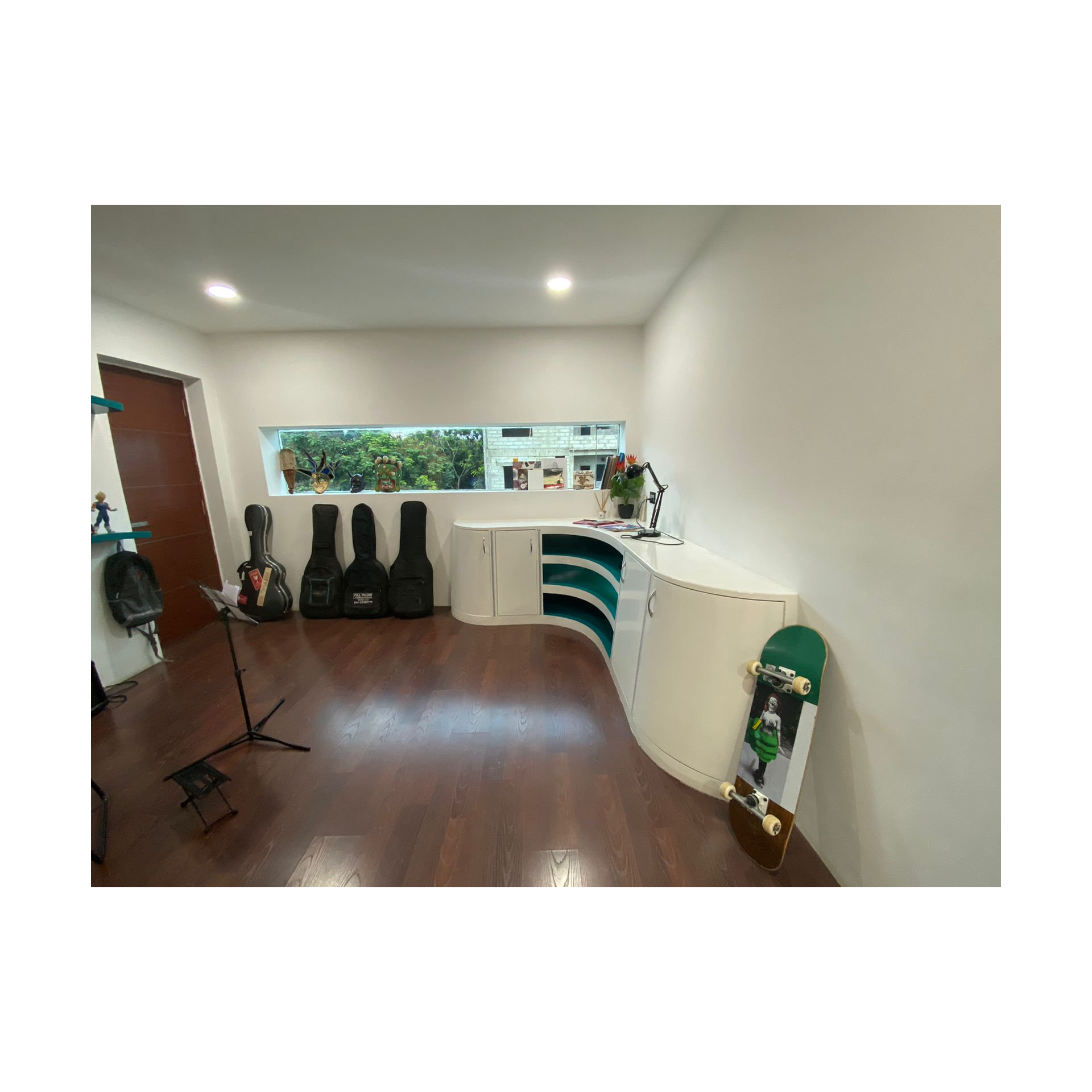 Music room corner with white storage units, teal niches, guitar cases and skateboard on dark wood flooring, Hyderabad
