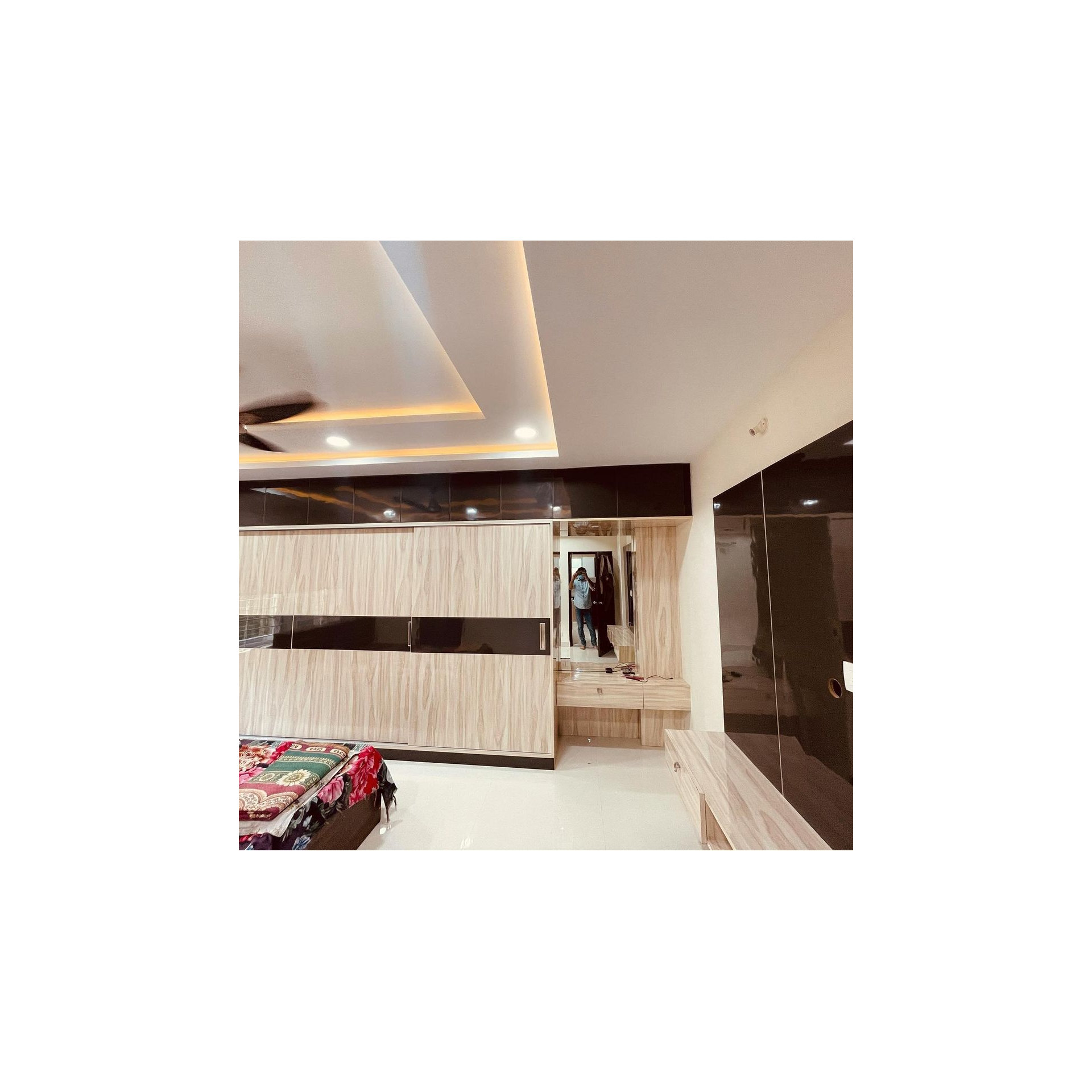 Bedroom wardrobe in light wood laminate with a dark glossy band, set under a layered false ceiling with cove lighting, Hyderabad