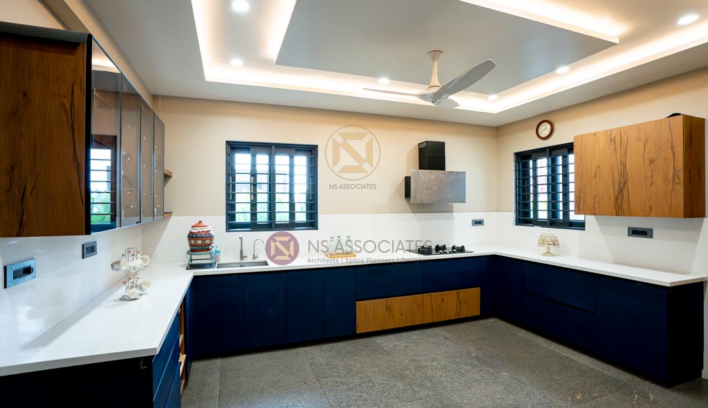 U-shaped kitchen pairing navy and woodgrain cabinetry under a cove-lit false ceiling, Hyderabad