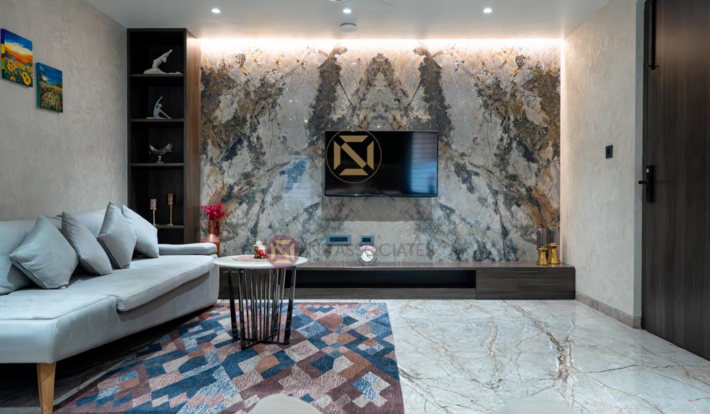 Living room featuring a book-matched marble TV wall, white sofa and geometric rug, Hyderabad