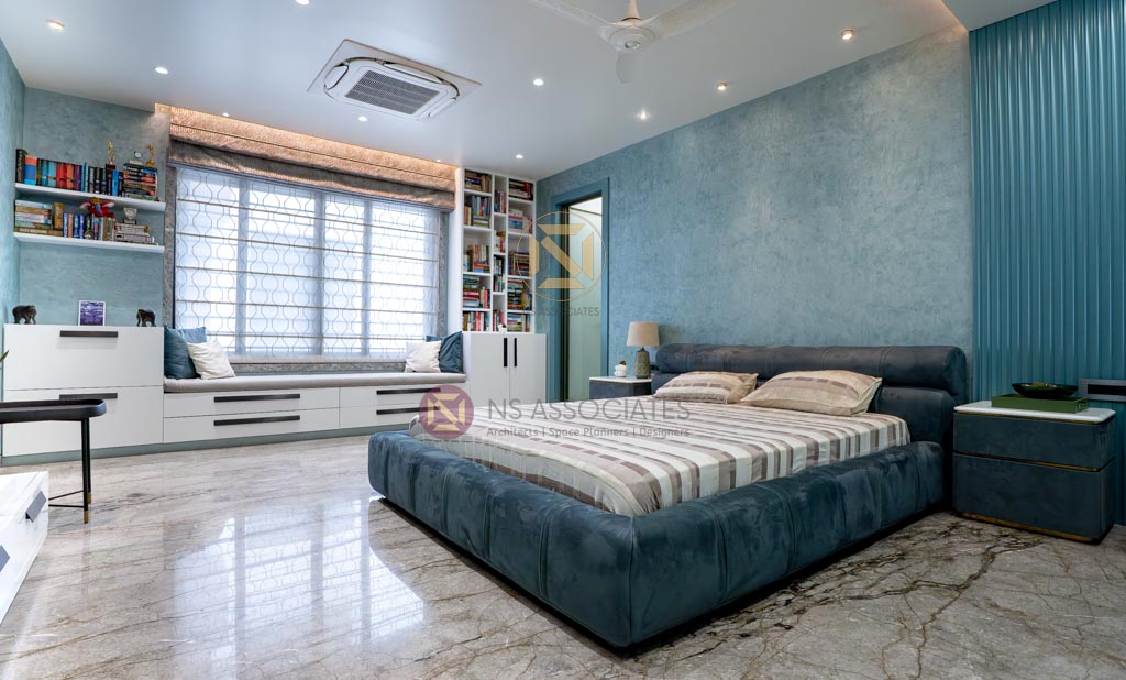 Teal-toned bedroom with upholstered bed, built-in bookshelves, window seat and glossy marble floor, Hyderabad