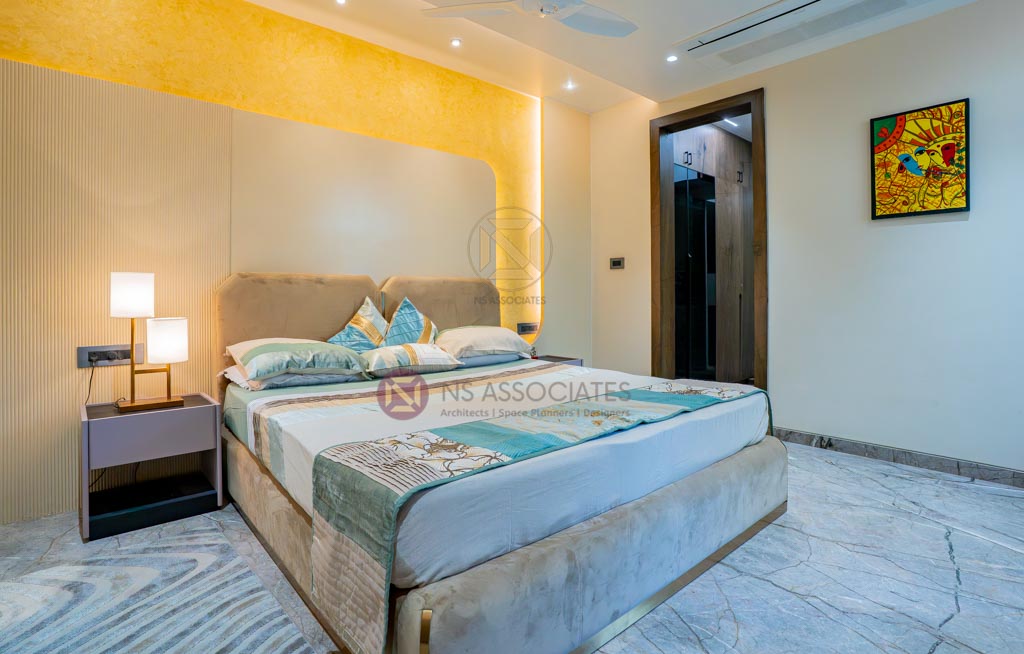 Bedroom with golden-yellow textured accent wall, upholstered bed and marble flooring, Hyderabad