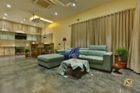 Open-plan living and kitchen with teal L-sofa, wood-grain cabinetry and a low carved coffee table on grey tile, Hyderabad