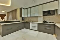 Modular kitchen with grey gloss base units, white quartz counters, marble backsplash and built-in gas hob