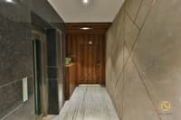 Entrance lobby with grey marble walls, slatted wood-panelled door and stone-look flooring under recessed lights, Hyderabad