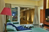 Living corner with teal sofa and red lamp beside sliding glass doors framing an illuminated textured stone wall, Hyderabad