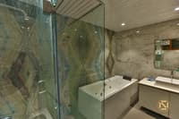 Bathroom clad in onyx and grey marble with glass shower enclosure, white jacuzzi tub and floating vanity, Hyderabad