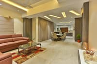 Open living-dining space with leather sofa, round dining set and layered cove-lit tray ceiling, Hyderabad home