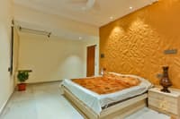 Bedroom with saffron 3D-textured accent wall, low wooden bed, floral spread and marble flooring, Hyderabad