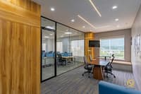 Glass-walled cabin with wood feature wall, mounted TV and window seat overlooking workstations, Hyderabad