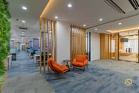 Office corridor with orange lounge chairs, vertical wood-slat screens, green living wall and glass-walled cabins, Hyderabad