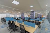 Wide open-plan office with rows of desks, blue partitions, branded columns and window-lit perimeter, Hyderabad