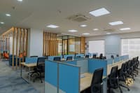 Corporate workstation bay with blue partitions, wood-slat divider screen and a wall whiteboard beside a glass cabin, Hyderabad