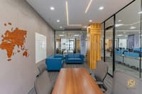 Breakout meeting area with carved wooden world-map wall art, whiteboard, blue armchairs and glass partitions, Hyderabad