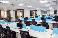 Open-plan office workstations in Hyderabad with white desks, blue privacy screens and black ergonomic chairs