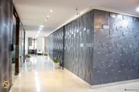 Office corridor in Hyderabad lined with a textured grey 3D tile feature wall and potted plants on glossy floors