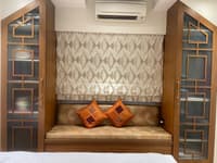 Cushioned window-seat alcove flanked by wood-and-glass fretwork panels under a geometric blind, Hyderabad bedroom