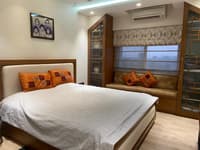 Bedroom with upholstered bed, orange patchwork cushions, fretwork wardrobes and a cushioned window-seat nook, Hyderabad