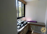 Cushioned window-seat nook with storage cabinets, folded mats and garden view, Hyderabad studio