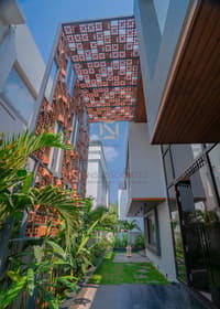 Side passage framed by a perforated terracotta jali screen and tropical palms, Hyderabad villa
