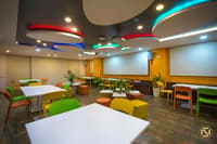 Training and cafeteria room with circular coloured ceiling lights, projector and bright green, yellow and orange seating, Hyderabad