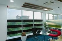 Breakout corner with black Swan chair, red lounge seat, glass table and panoramic city-view windows, Hyderabad
