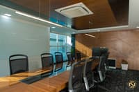 Conference room with timber table, black chairs, wall-mounted display screen and diamond-patterned wood panelling, Hyderabad office