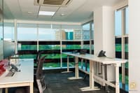 Open workstation bay with white height-adjustable desks and floor-to-ceiling tinted glazing overlooking the city, Hyderabad