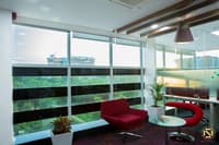 Office lounge area with red armchairs, pendant light and zebra blinds over wide glazing, Hyderabad