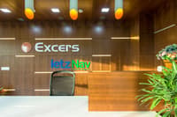 Reception desk against backlit walnut wood wall with illuminated Excers and letzNav branding, Hyderabad corporate fit-out