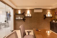 Private office cabin with wooden desk, grey leather chair, framed certificates on a textured tan wall and recessed lighting, Hyderabad