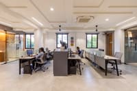 Open-plan workstation floor with staff at desks, monitors, ergonomic chairs and a coffered white ceiling in Hyderabad