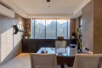 Director's cabin with glass-top desk, brown textured walls, dark credenza and a wide window overlooking greenery, Hyderabad
