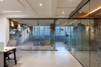 Open office with glass-walled cabins, fluted glass partitions, recessed ceiling lights and polished concrete floors in Hyderabad