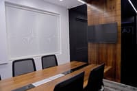 Meeting room with wood-top table, patterned roller blind, wall TV and walnut panelling, Hyderabad office