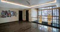 Marble-floored foyer with framed photo gallery wall, decorative metal screen and gold chandeliers, Hyderabad