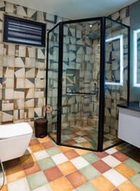 Bathroom with multicoloured geometric patterned tiles, glass shower enclosure and backlit LED mirror, Hyderabad