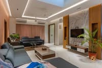 Living room with marble and wood-slat TV wall, grey leather sofas, low coffee table and potted palm, Hyderabad