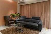 Living room with charcoal three-seater sofa, leather accent chair and round glass coffee table on a shaggy rug, Hyderabad