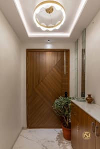 Entrance foyer with chevron-pattern teak wood door, ring chandelier in a cove ceiling and marble flooring, Hyderabad