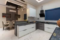 Modular kitchen with L-shaped white and grey cabinets, marble backsplash, gas hob and adjoining dining nook, Hyderabad