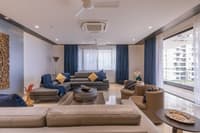 Living room with tan leather sofas, navy curtains, round coffee table and balcony view, Hyderabad apartment